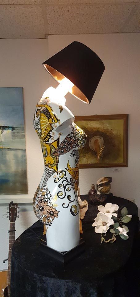 In einem Raum steht eine Lampe auf einer Schaufensterpuppe.