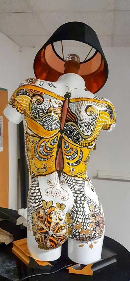 Eine Frauenstatue mit einer Lampe darauf.