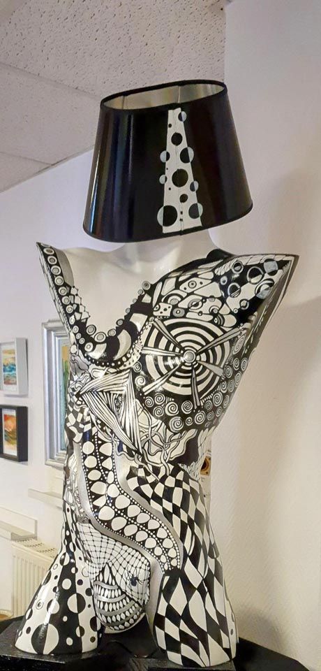 Auf einem Tisch steht eine schwarz-weiße Lampe mit schwarzem Schirm.