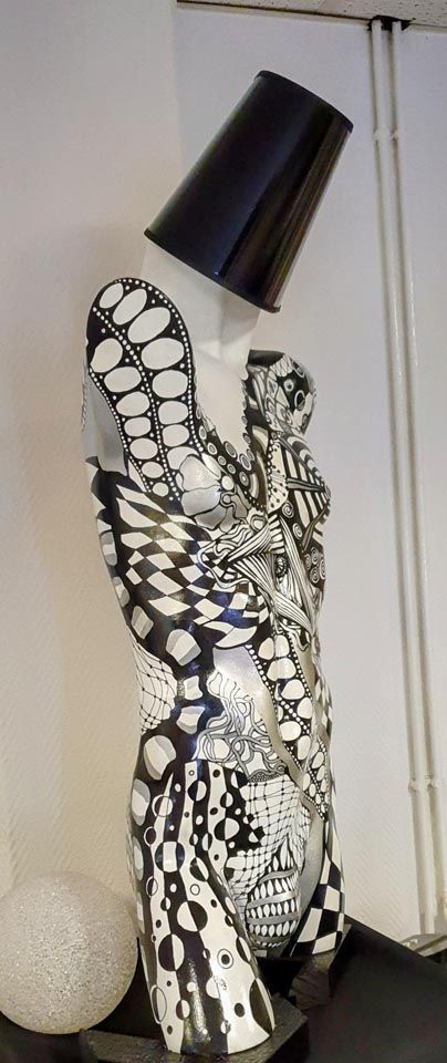 Eine schwarz-weiße Statue einer Frau mit einer Lampe auf dem Kopf.