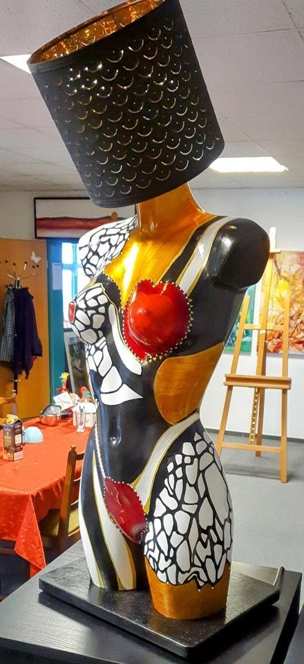 Eine Statue einer Frau, die einen Apfel und eine Lampe hält.