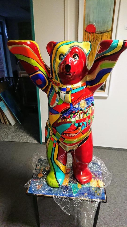 Eine bunte Teddybärstatue sitzt auf einem Tisch.