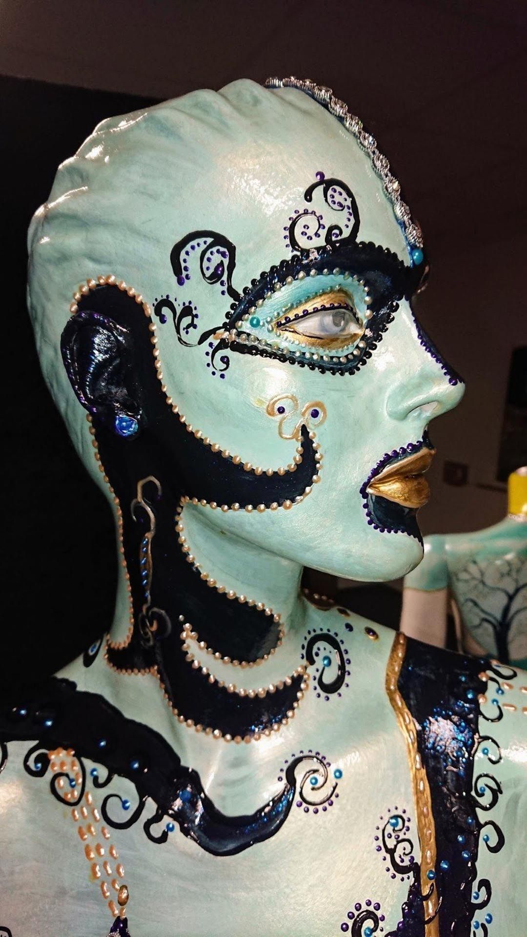 Eine Nahaufnahme der Statue einer Frau mit einer Maske im Gesicht.