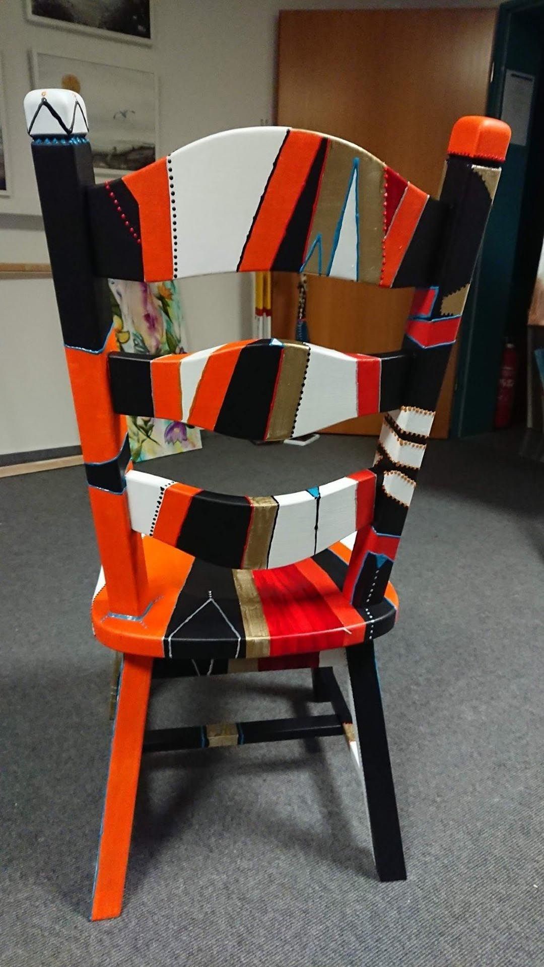 In einem Zimmer steht ein bunter Stuhl auf einem mit Teppichboden ausgelegten Boden.