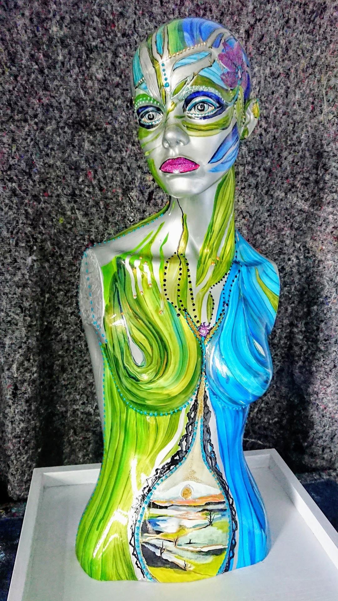 Eine farbenfrohe Frauenstatue sitzt auf einem Tisch.