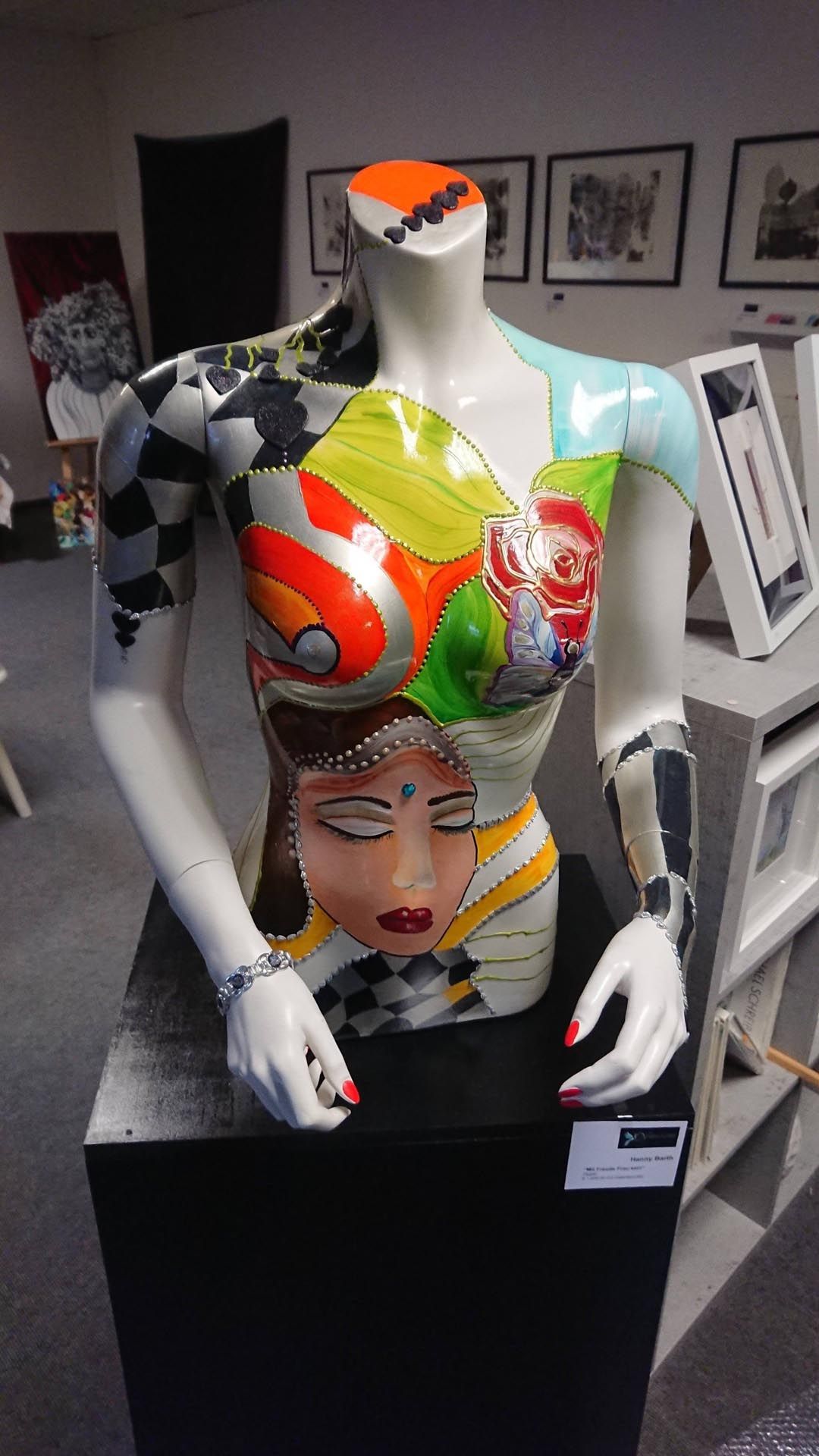 In einem Raum ist eine farbenfrohe Statue eines Frauentorsos ausgestellt.