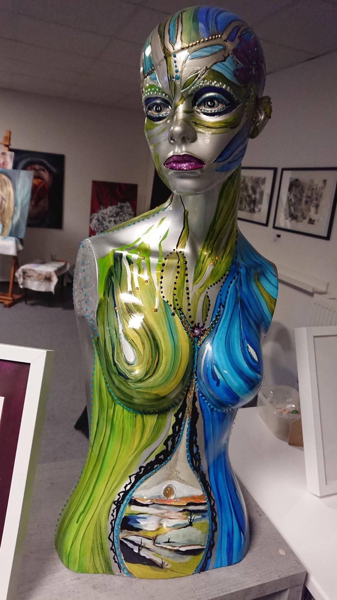 Auf einem Tisch sitzt eine farbenfrohe Statue eines Frauentorsos.