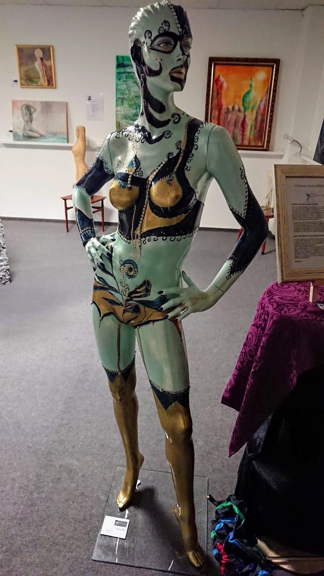 In einem Raum steht die Statue einer Frau, die Hände in die Hüften gestemmt.