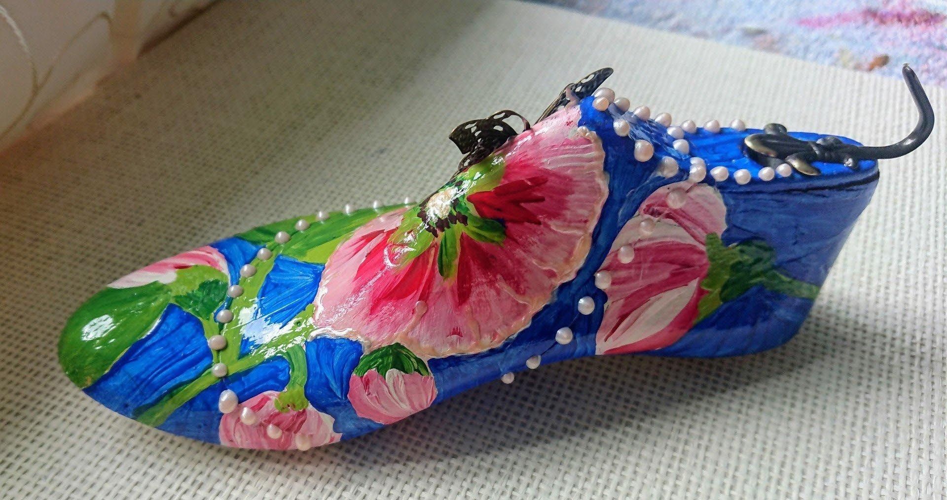 Ein blauer Schuh mit rosa Blumen darauf gemalt