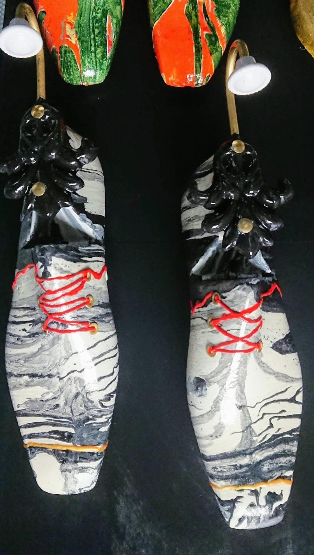 Ein Paar Schuhe mit roten Schnürsenkeln hängen an einer Wand