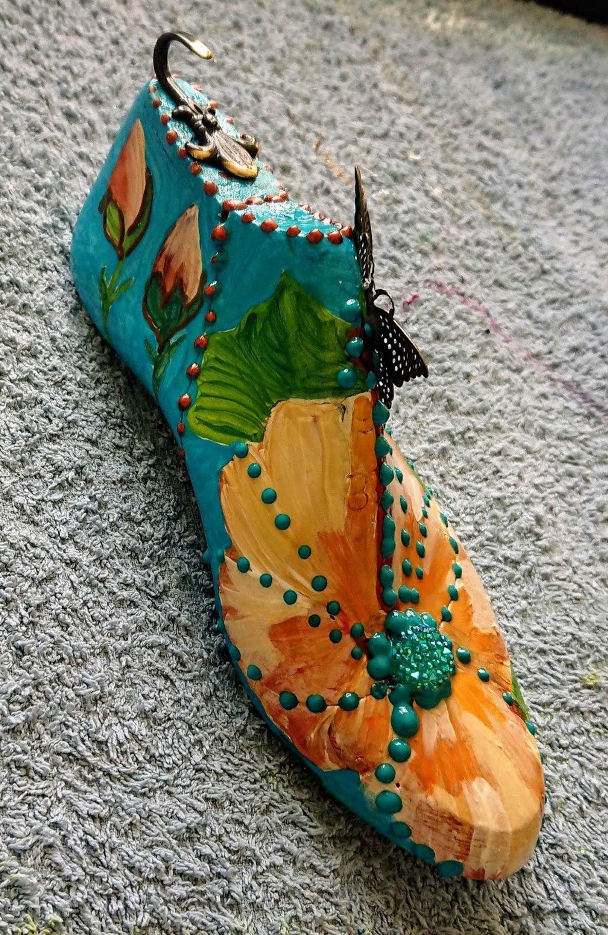 Auf einem Teppich steht ein mit Blumen aufgemalter Schuh.