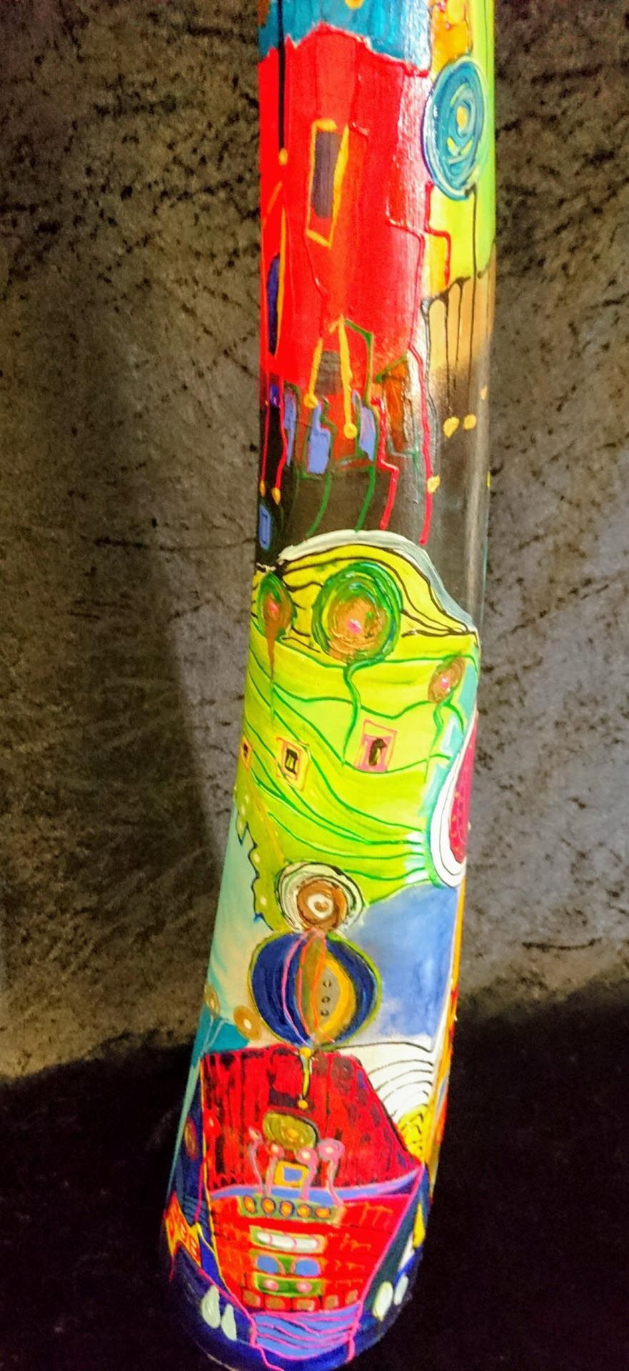 Auf einem Tisch steht eine bunte Vase mit einem Gemälde darauf.