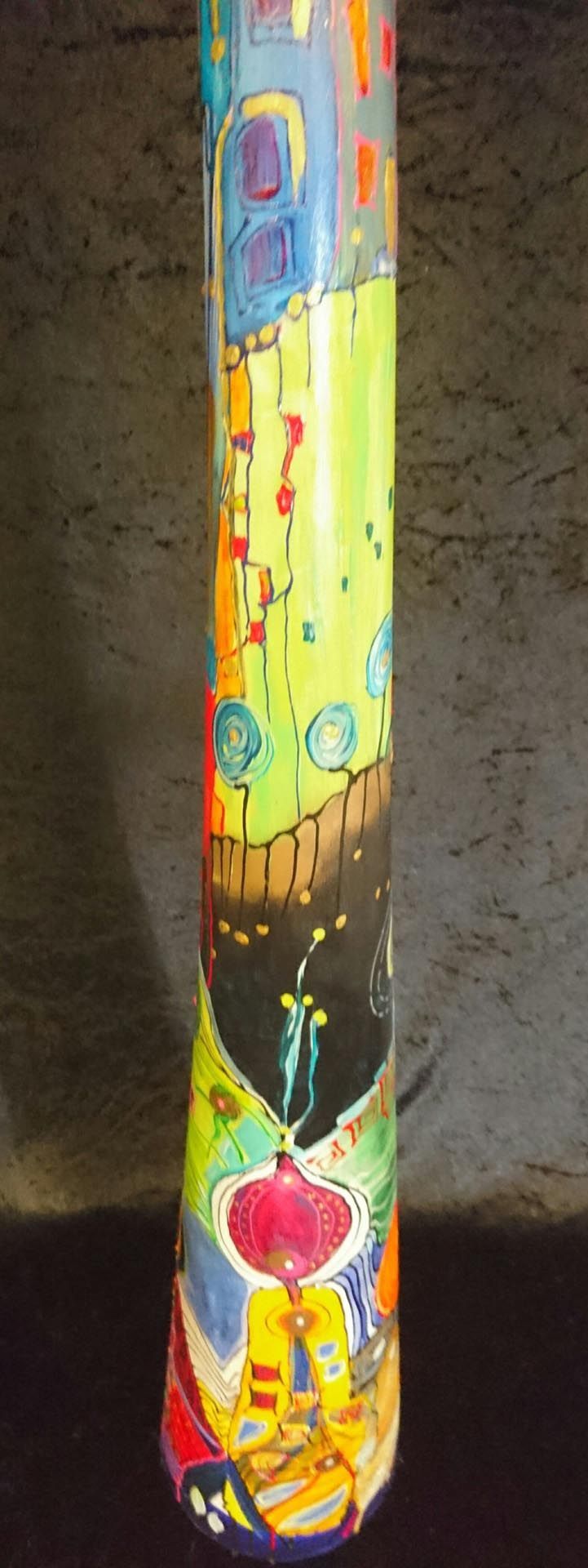 Auf einem Tisch steht eine bunte Vase mit einem Gemälde darauf.