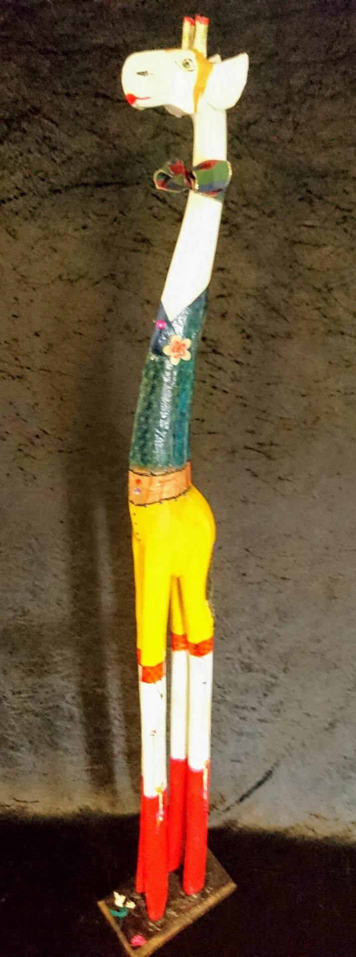 Eine Statue einer Giraffe mit Hut und gelben Hosen.