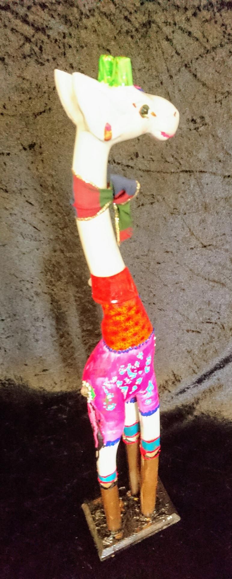 Eine Statue einer Giraffe mit grünem Hut und rosa Shorts.