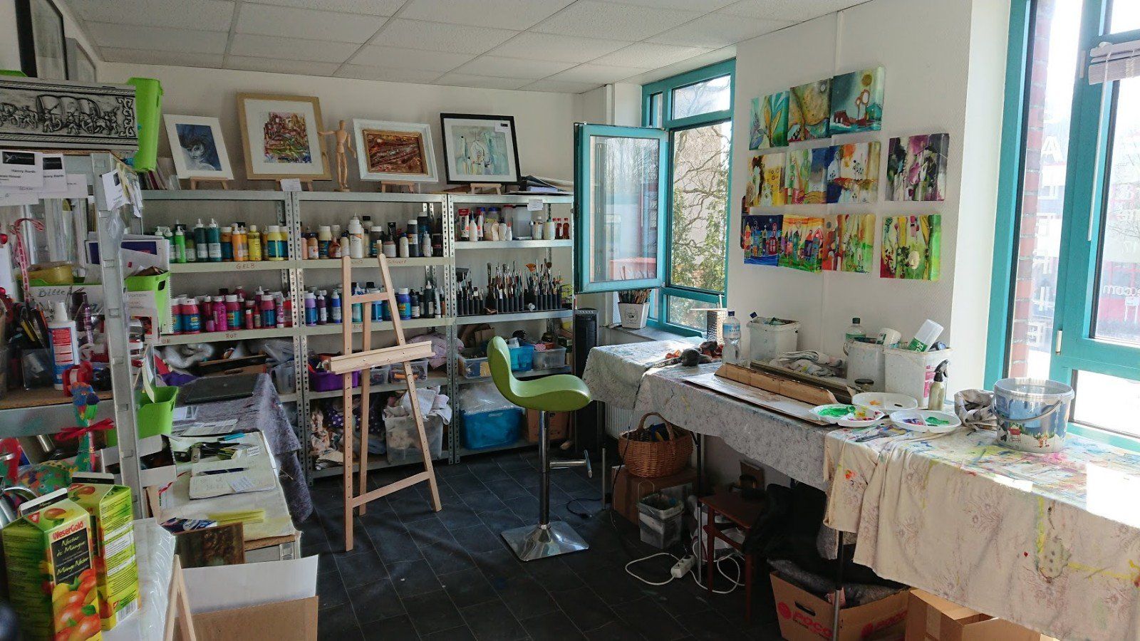 Ein Raum voller Kunstbedarf und Gemälde an den Wänden.