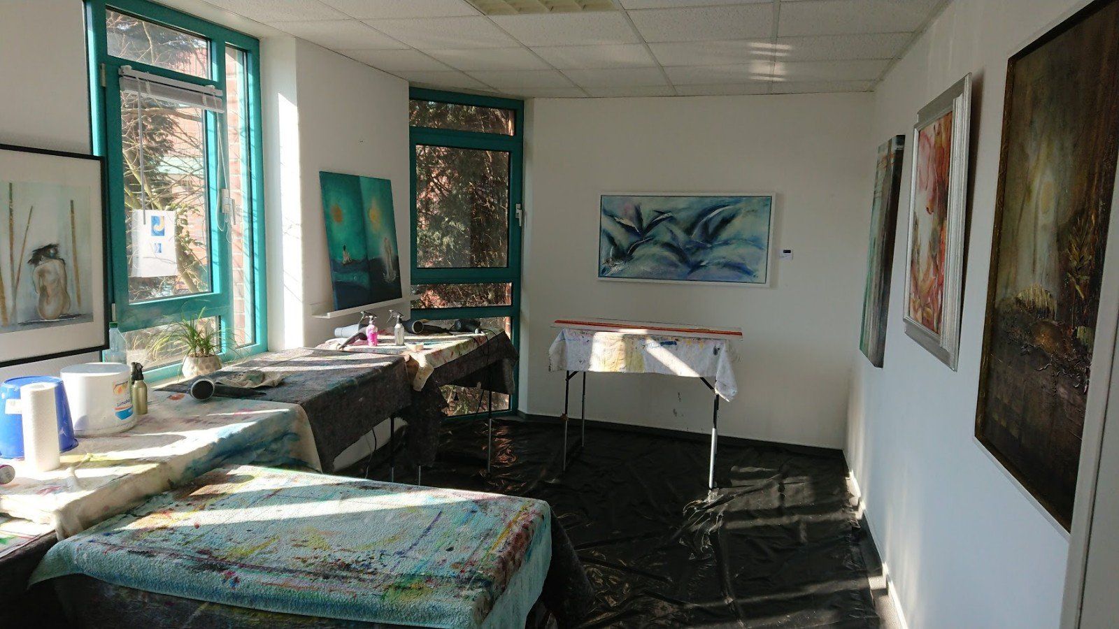 Ein Raum mit Tischen und Stühlen und Gemälden an den Wänden.