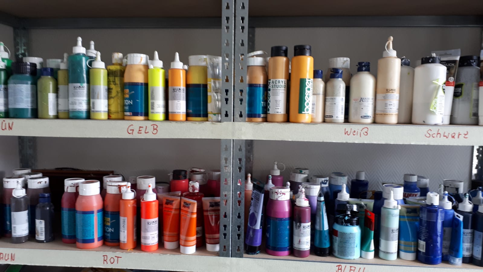Ein Regal voller Farbflaschen, darunter Gold