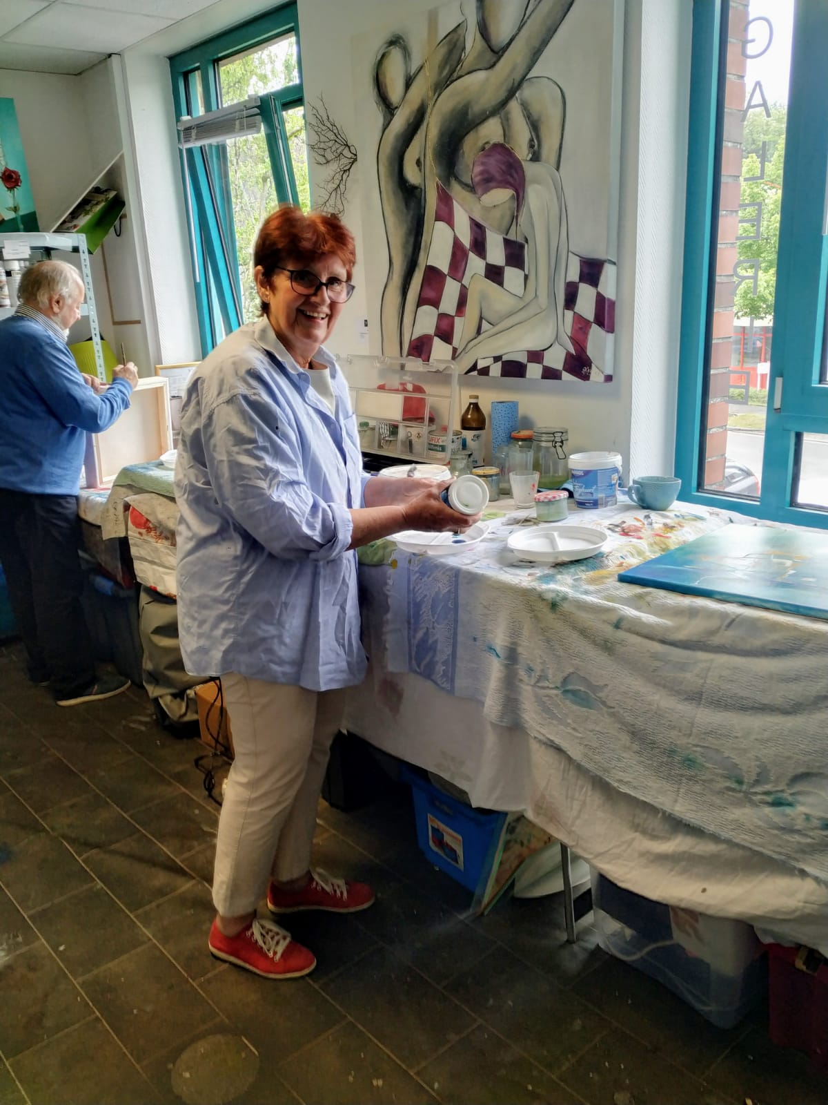 Eine Frau steht vor einem Tisch, hinter ihr hängt ein Gemälde an der Wand.