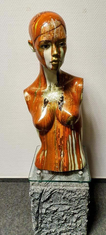 Auf einem Glastisch sitzt eine Statue eines Frauentorsos.