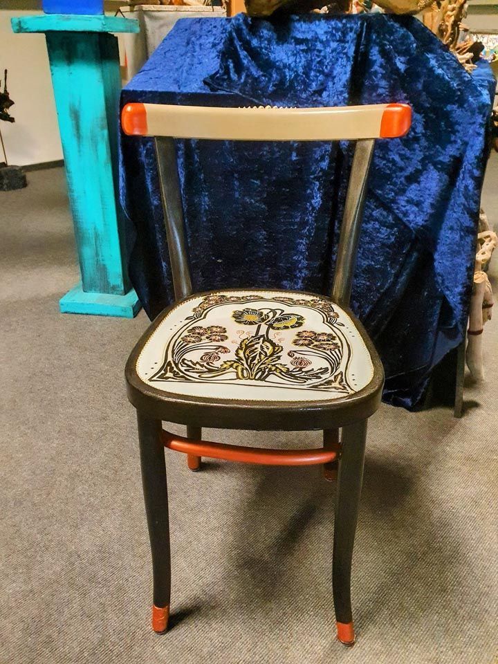 Auf einem Tisch steht ein Stuhl mit einem Gemälde auf der Sitzfläche.