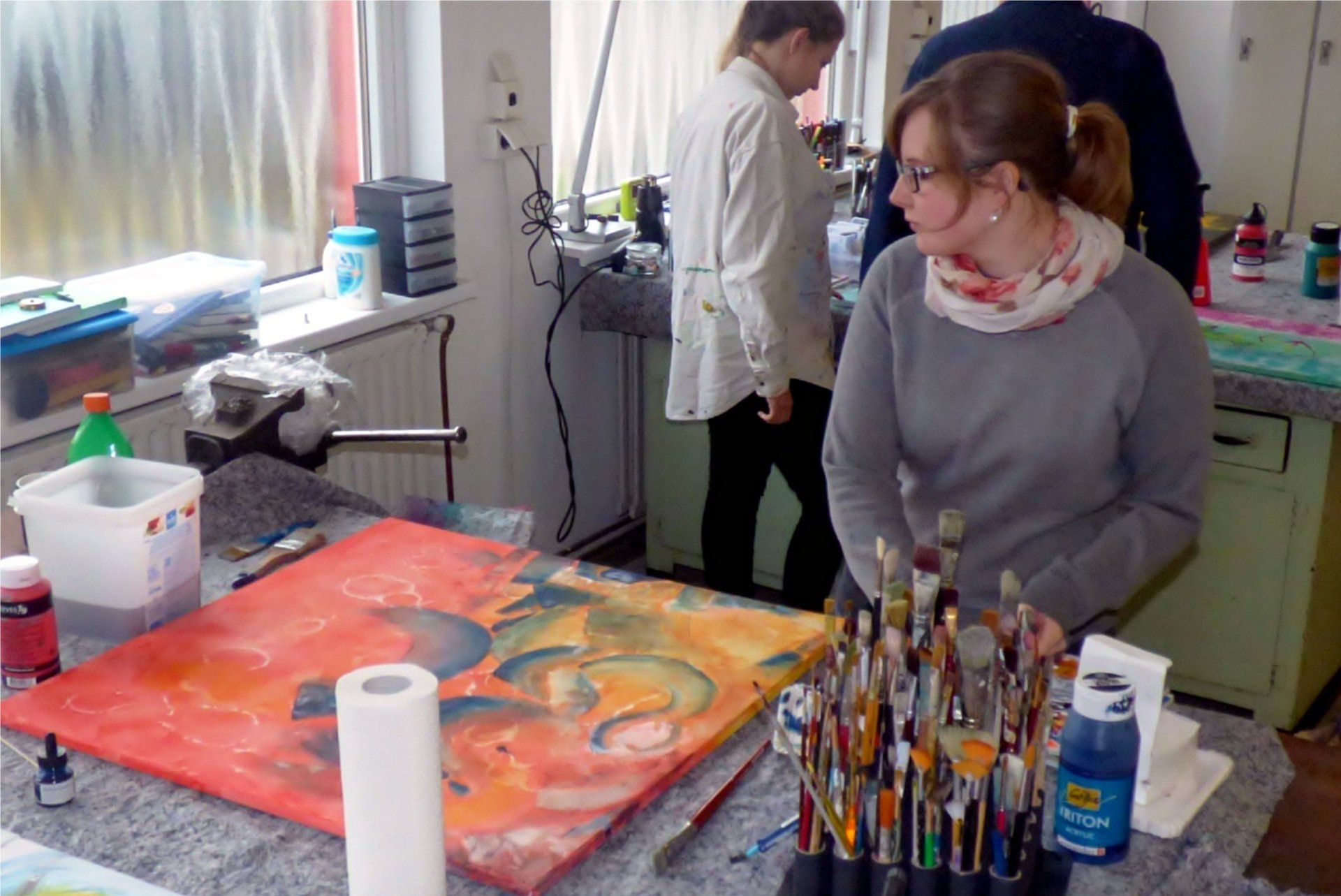 Eine Frau sitzt an einem Tisch mit einem Gemälde darauf