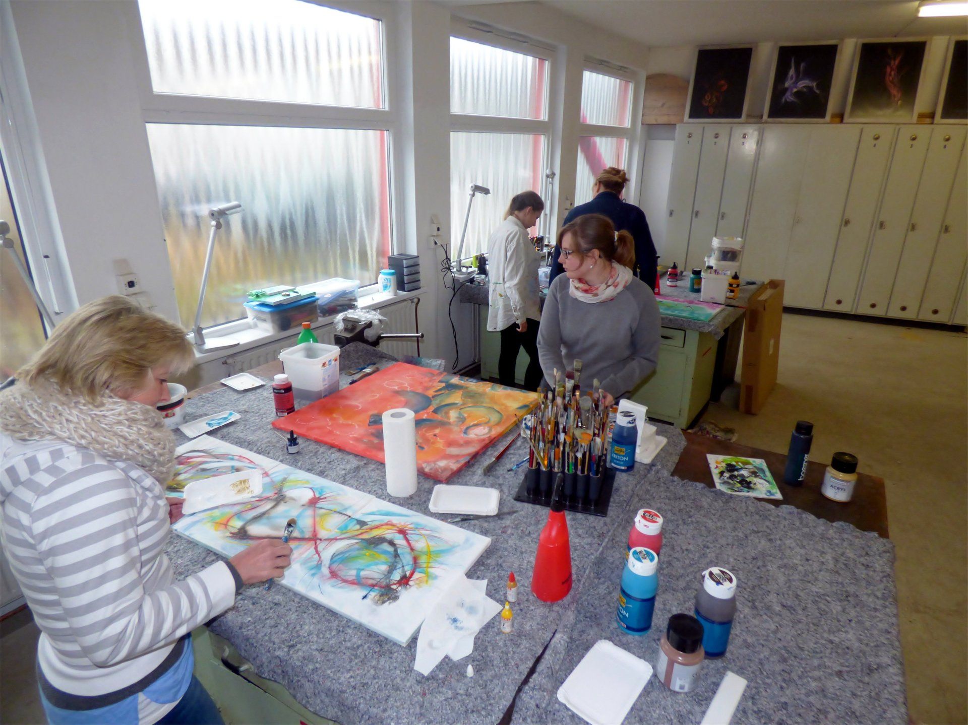 Eine Gruppe Leute sitzt an einem Tisch und malt ein Bild.