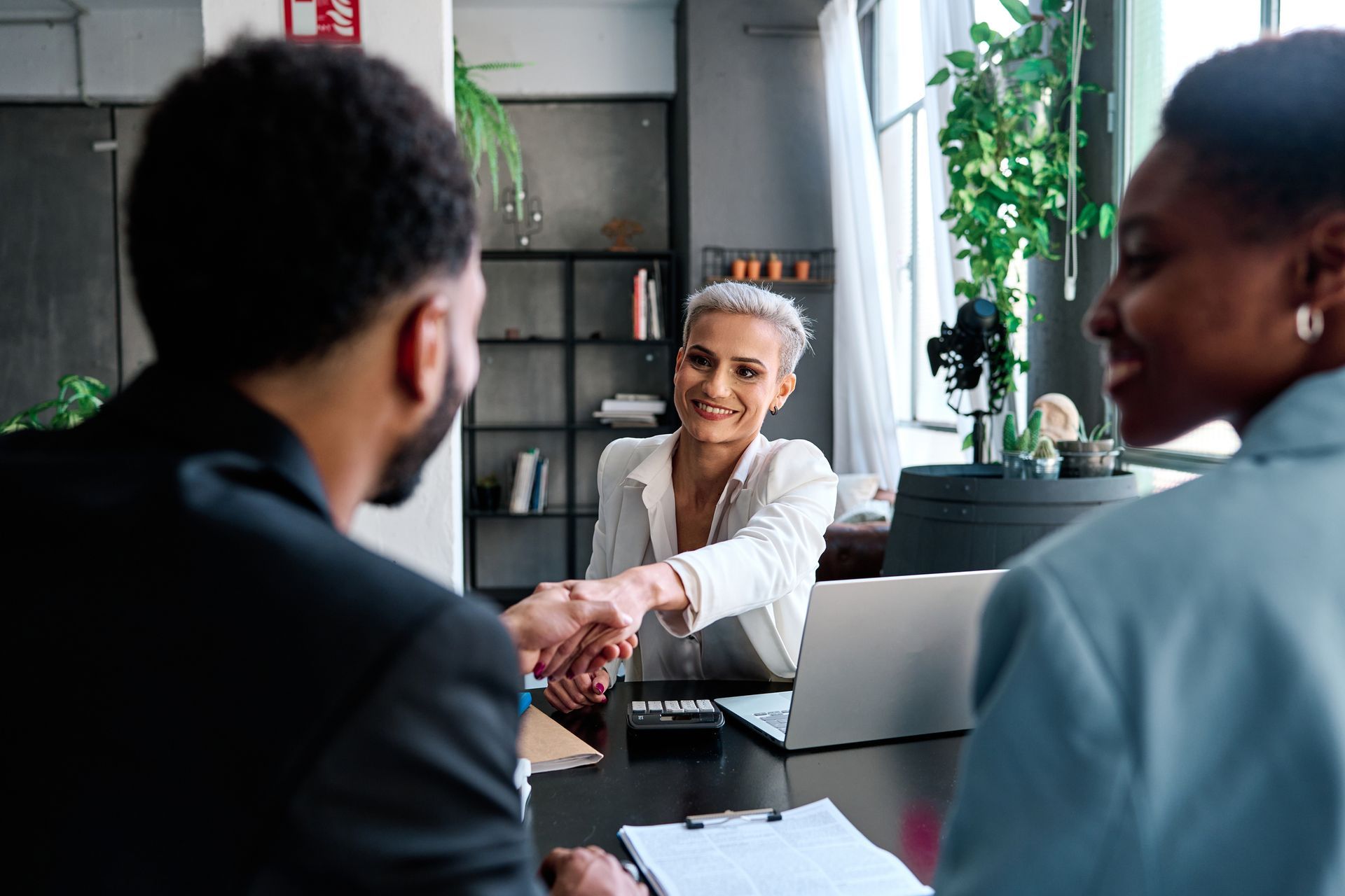 A woman is shaking hands with a man during a job interview.