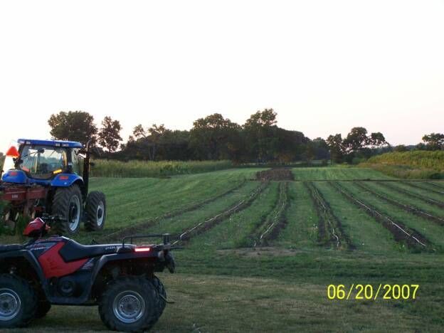 A red atv is parked next to a blue tractor in a field