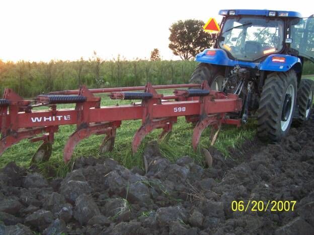 A white tractor is plowing a field in 2007