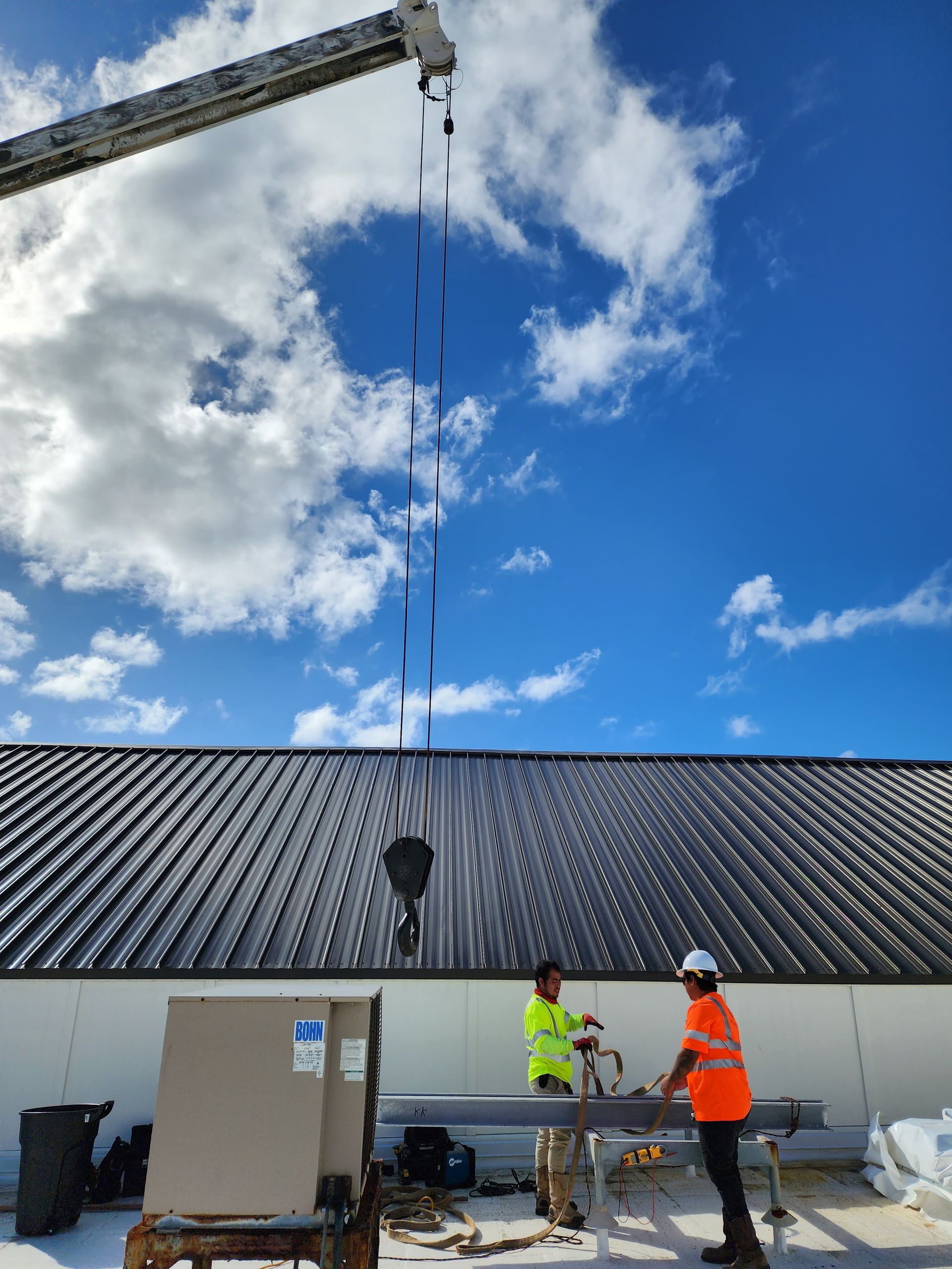 Two construction workers are working on the roof of a building.