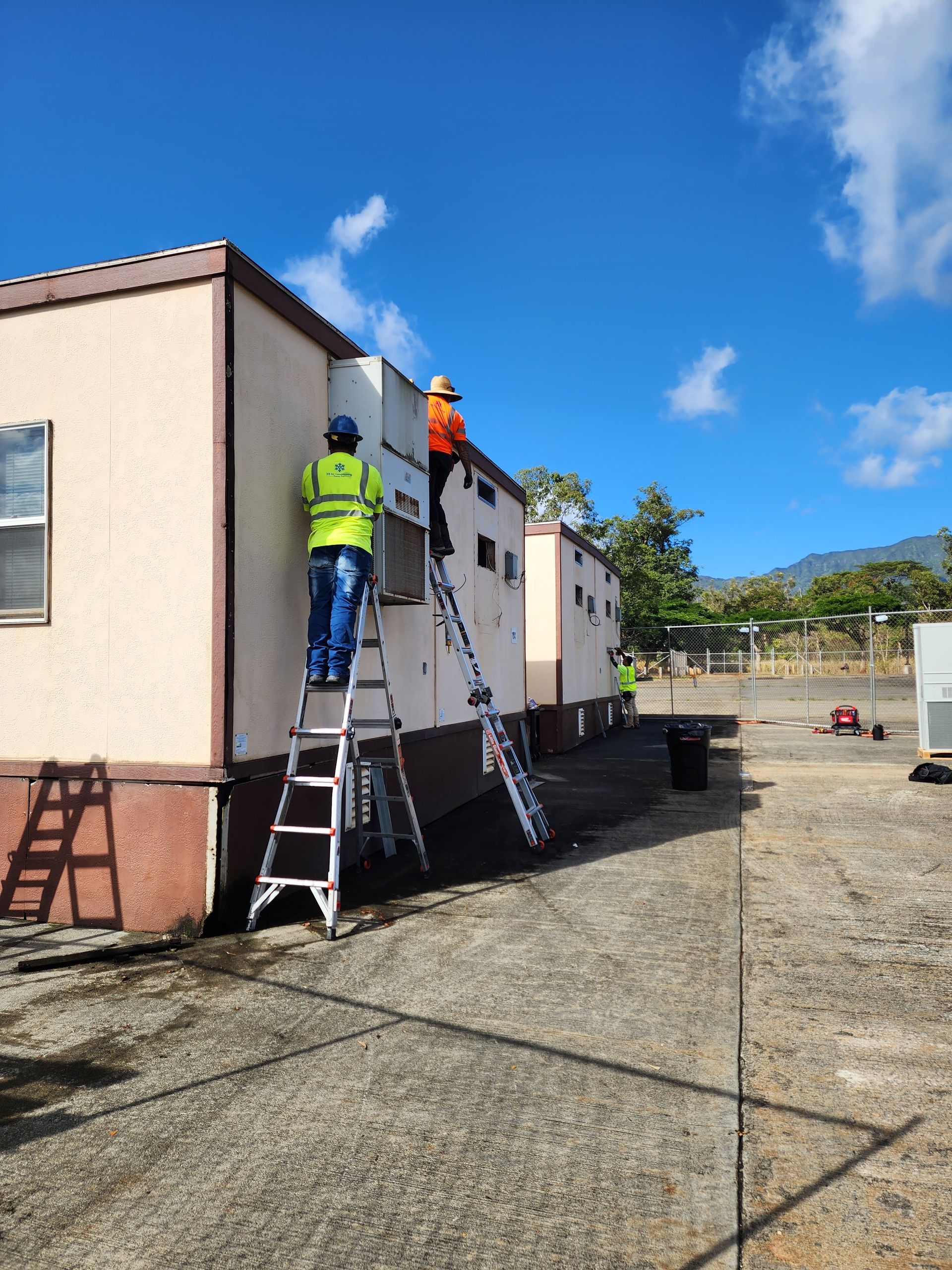 Two men are working on the side of a building.