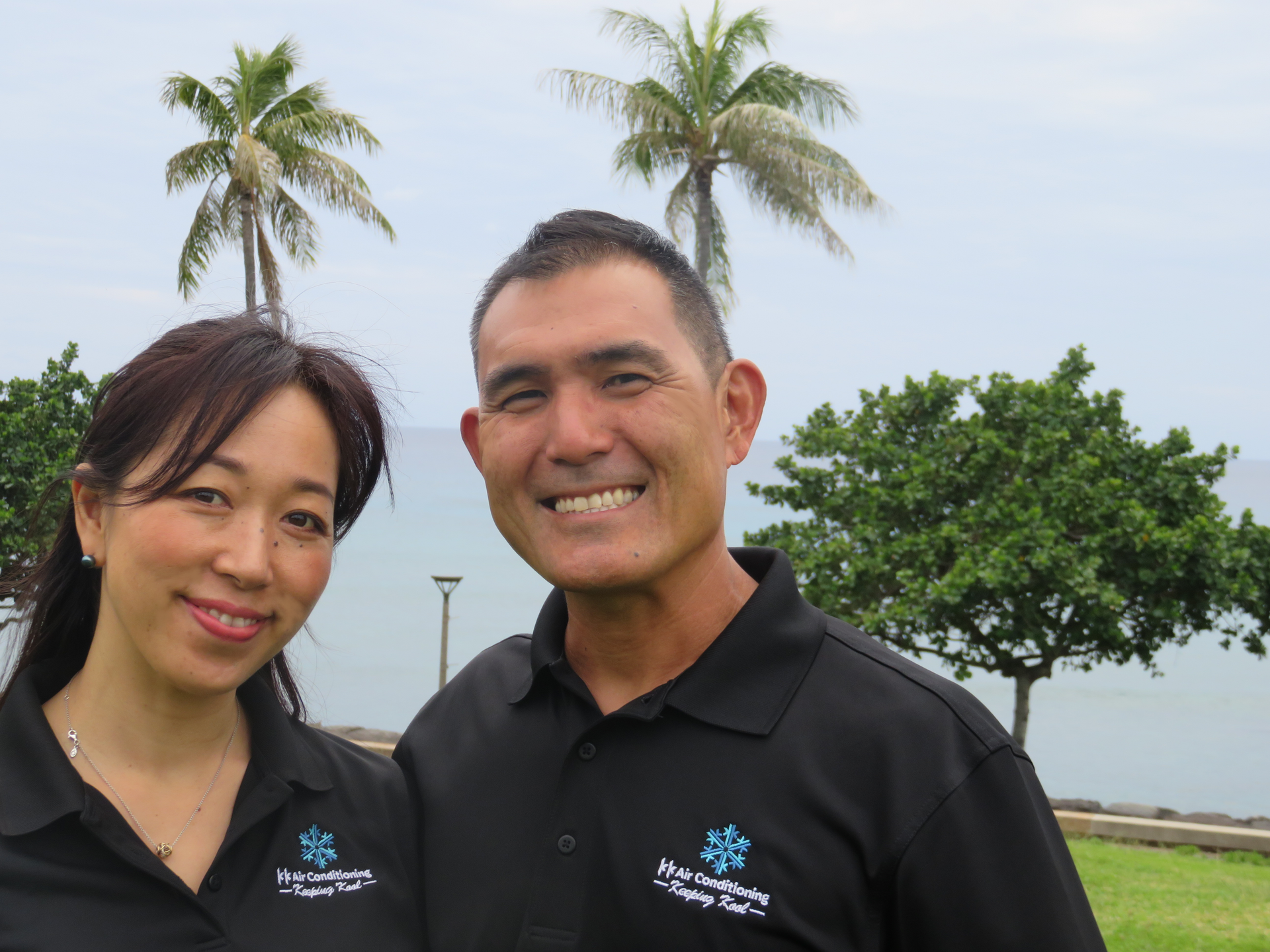 A man and a woman are posing for a picture with palm trees in the background