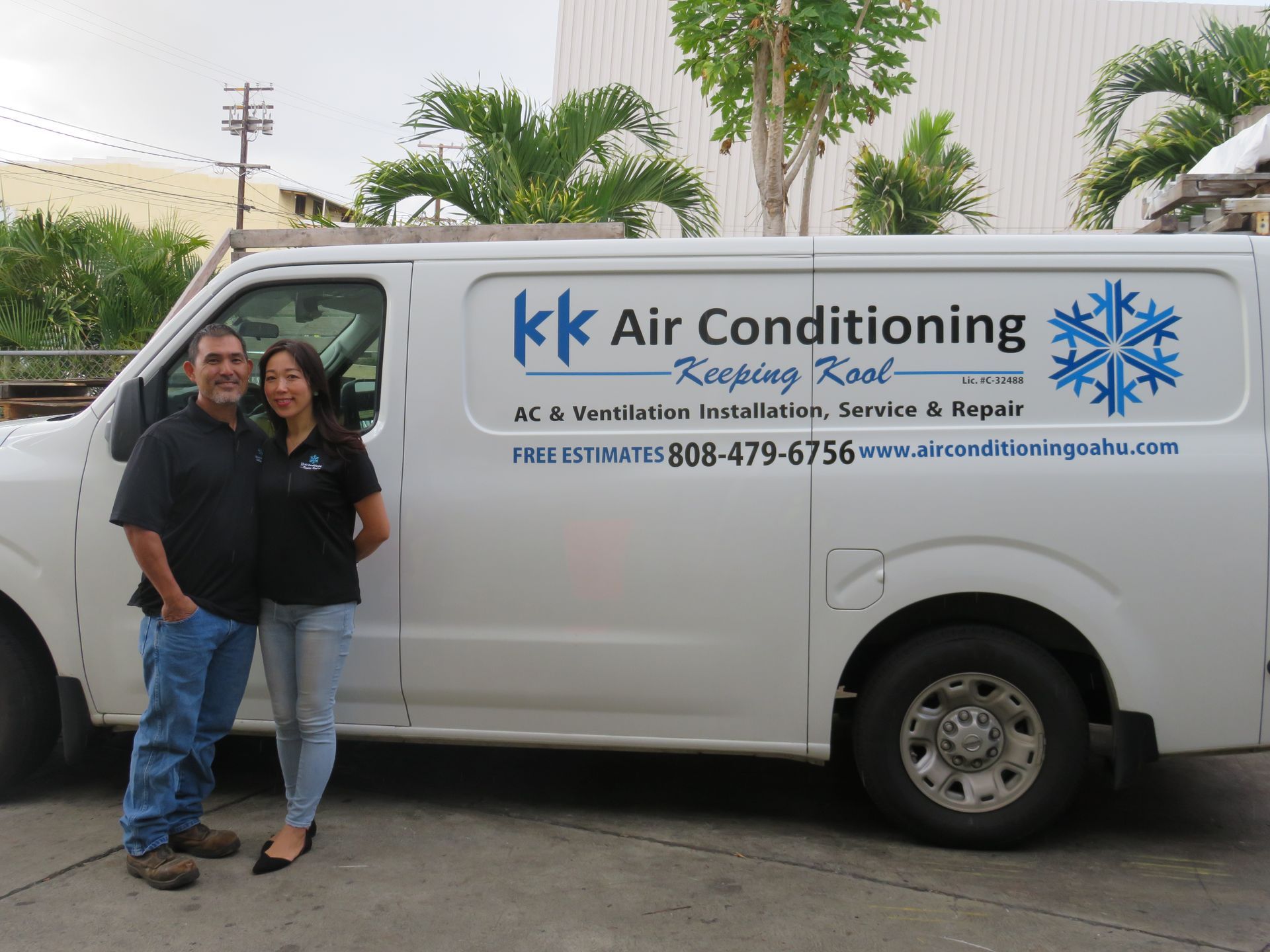 A man and a woman are standing in front of a white van that says kk air conditioning.