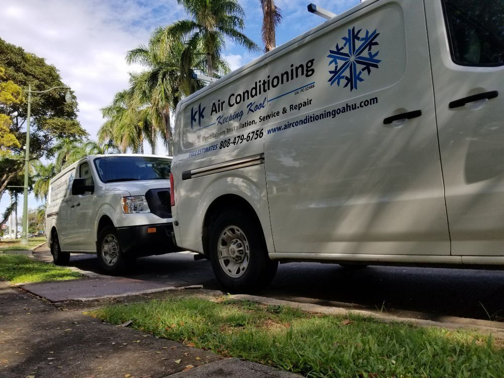 Two white vans are parked on the side of the road.