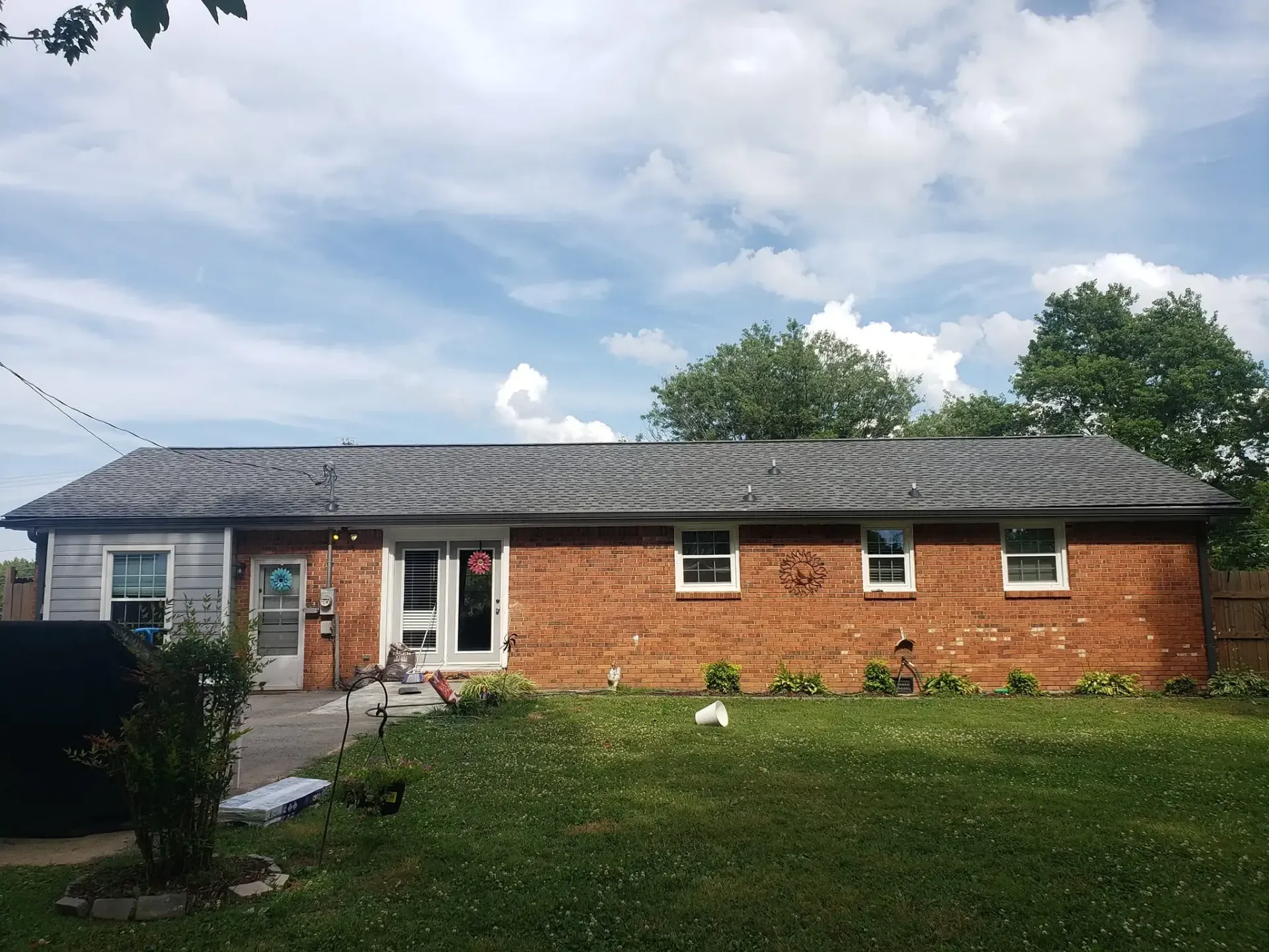 A brick house with a gray roof and blue sky. Green lawn in the foreground.