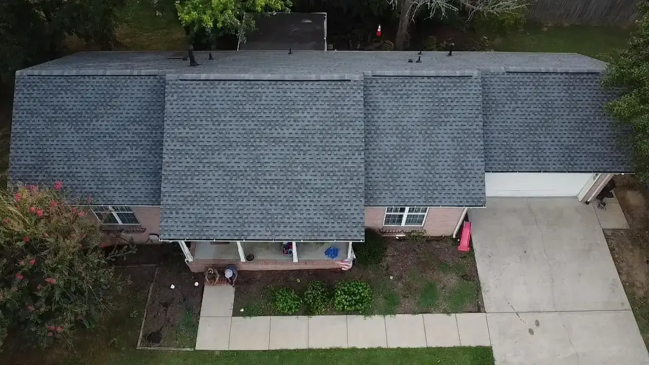 Overhead view of a house with a gray roof, white garage door, and a concrete path leading to the front porch.