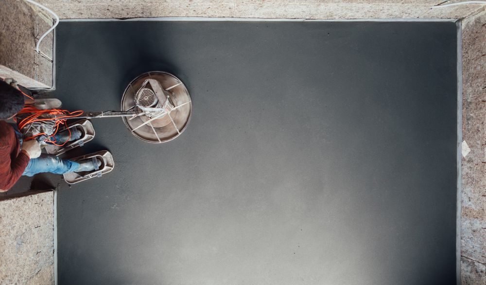 A Man is Using a Machine to Polish a Black Floor — Wayne Hall Concreting in Ballina, NSW