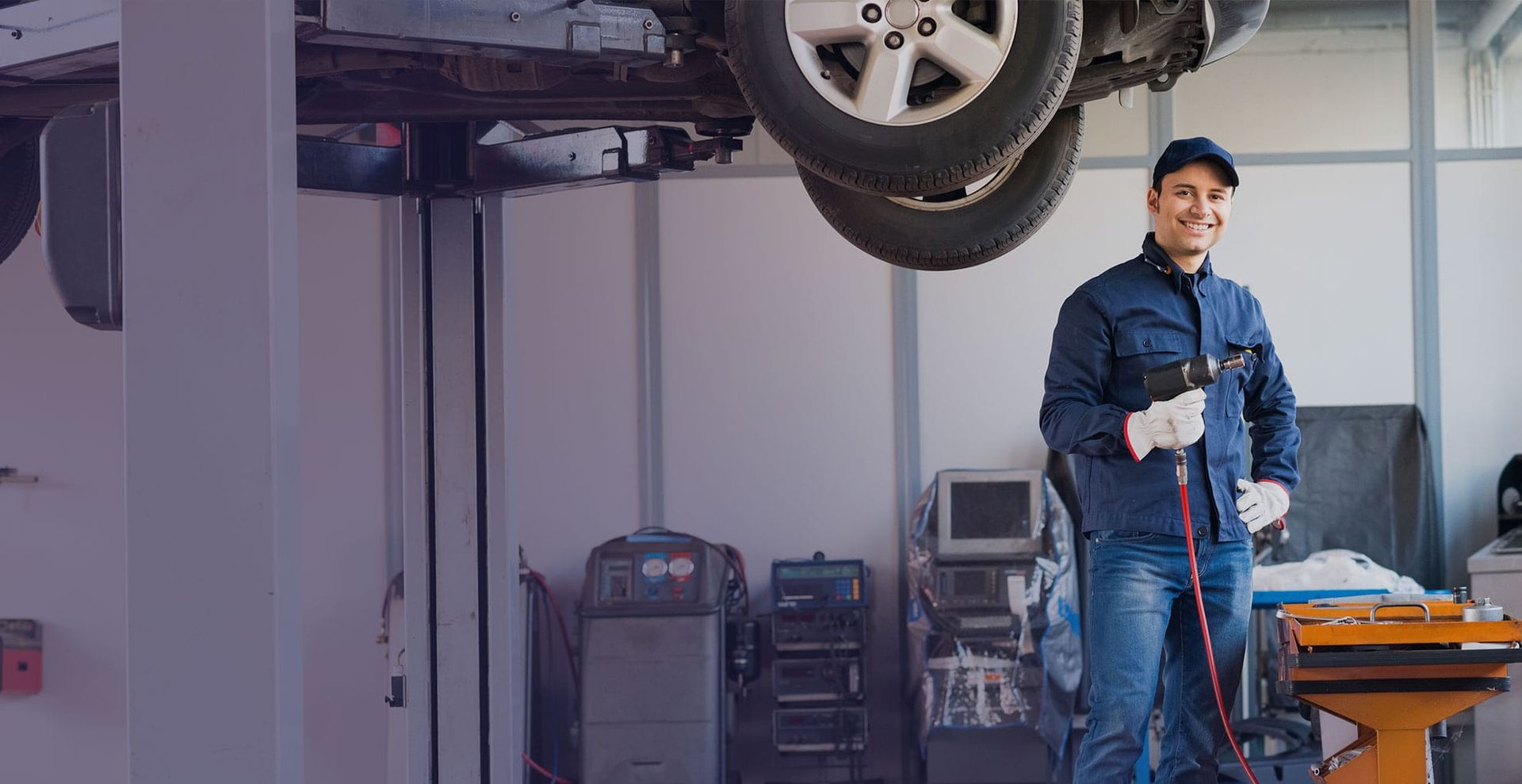 A Man Is Standing In Front Of A Car On A Lift In A Garage β Coffs Harbour Automotive In Coffs Harbour, NSW