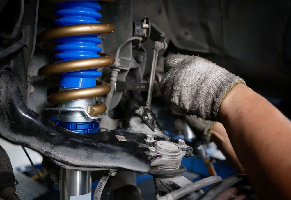 A Person Is Working On A Shock Absorber On A Car — Coffs Harbour Automotive In Coffs Harbour, NSW