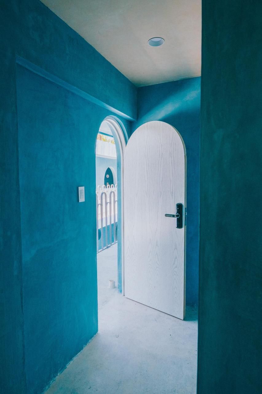 Un pasillo con paredes azules y una puerta blanca.