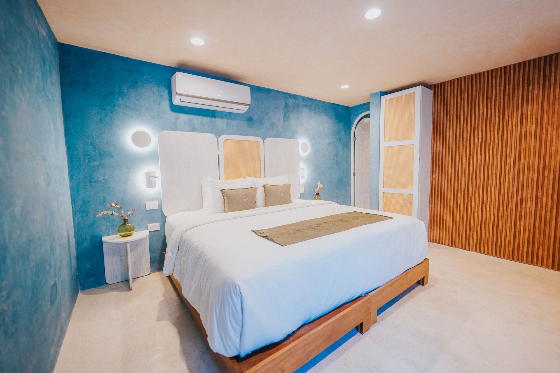 Dormitorio con cama King, pared texturizada azul y detalles de madera.