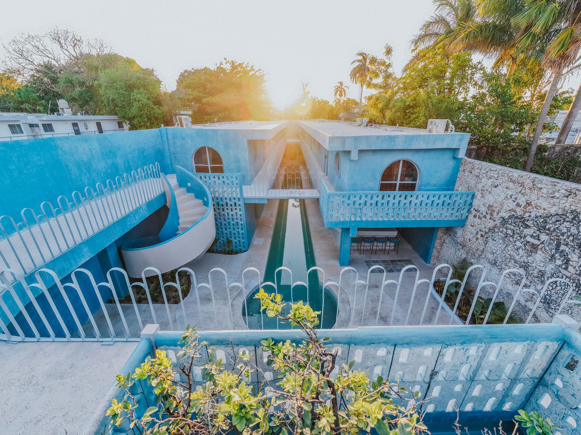 Edificio de estilo Art Decó de color turquesa con escalera de caracol y puesta de sol al fondo.