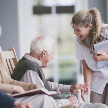 a nurse laughs while talking to an elderly man