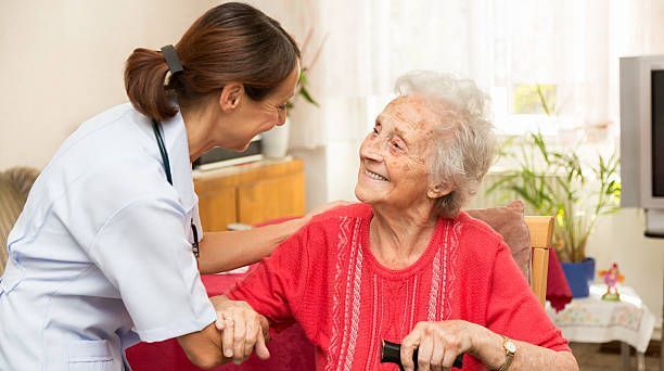 caregiver helping elderly woman in assisted living facility