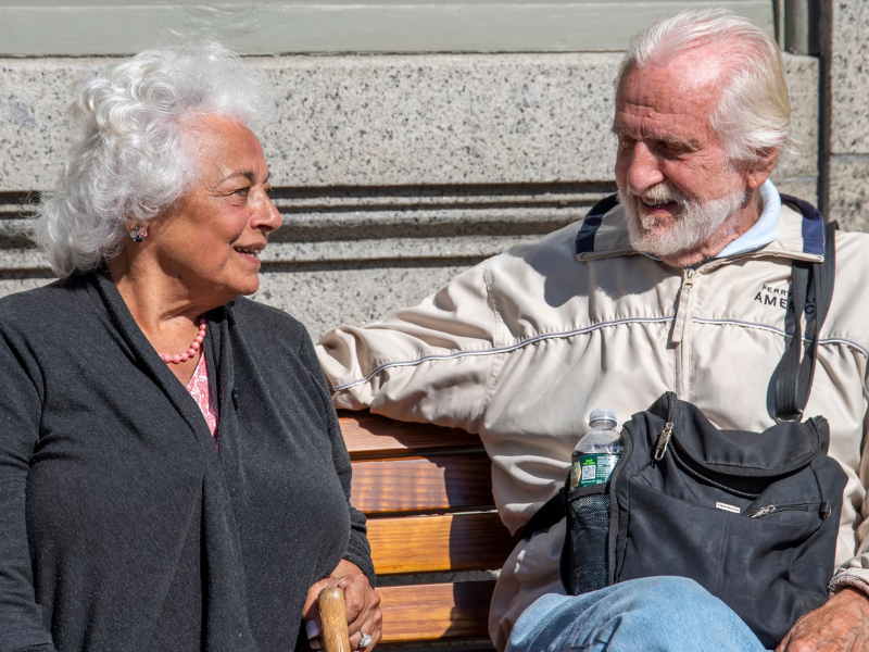 elderly couple sitting on a bench together 