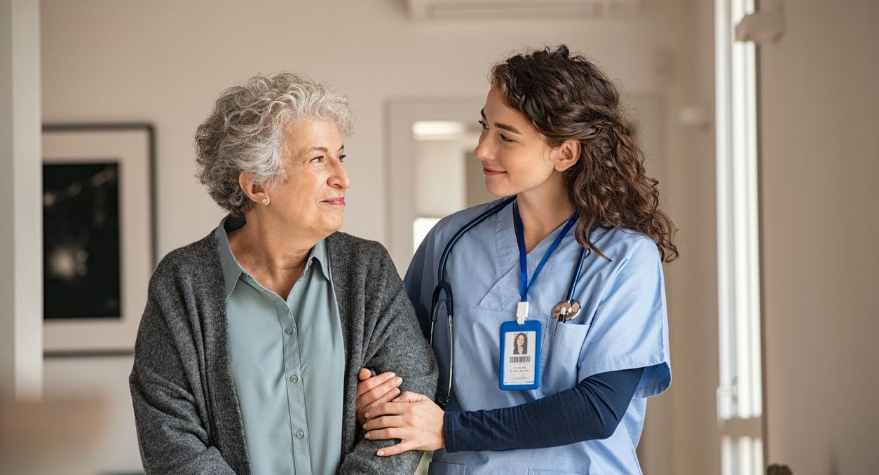 nurse helping senior woman in assisted living facility