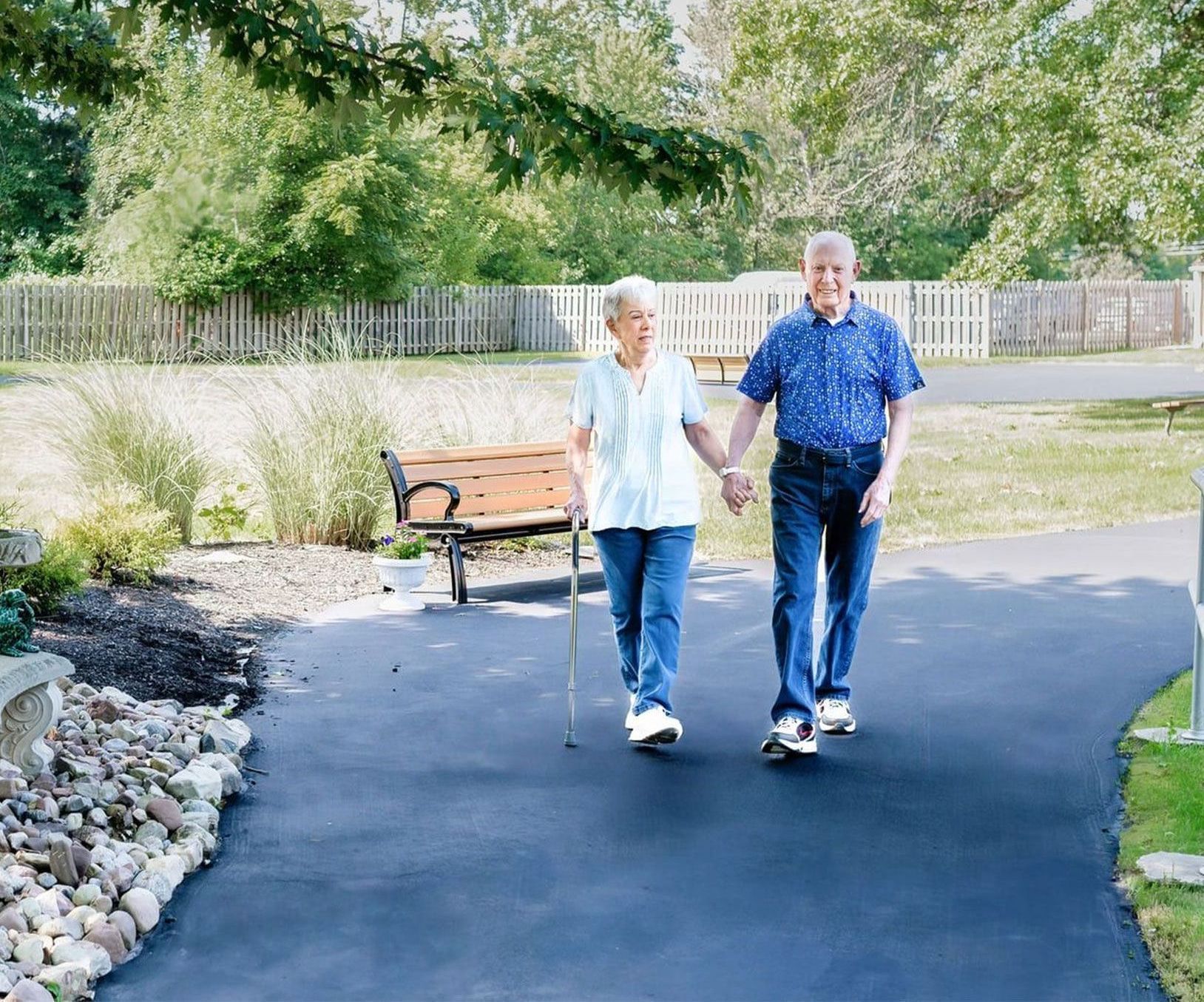 A man and woman are walking down a path holding hands.