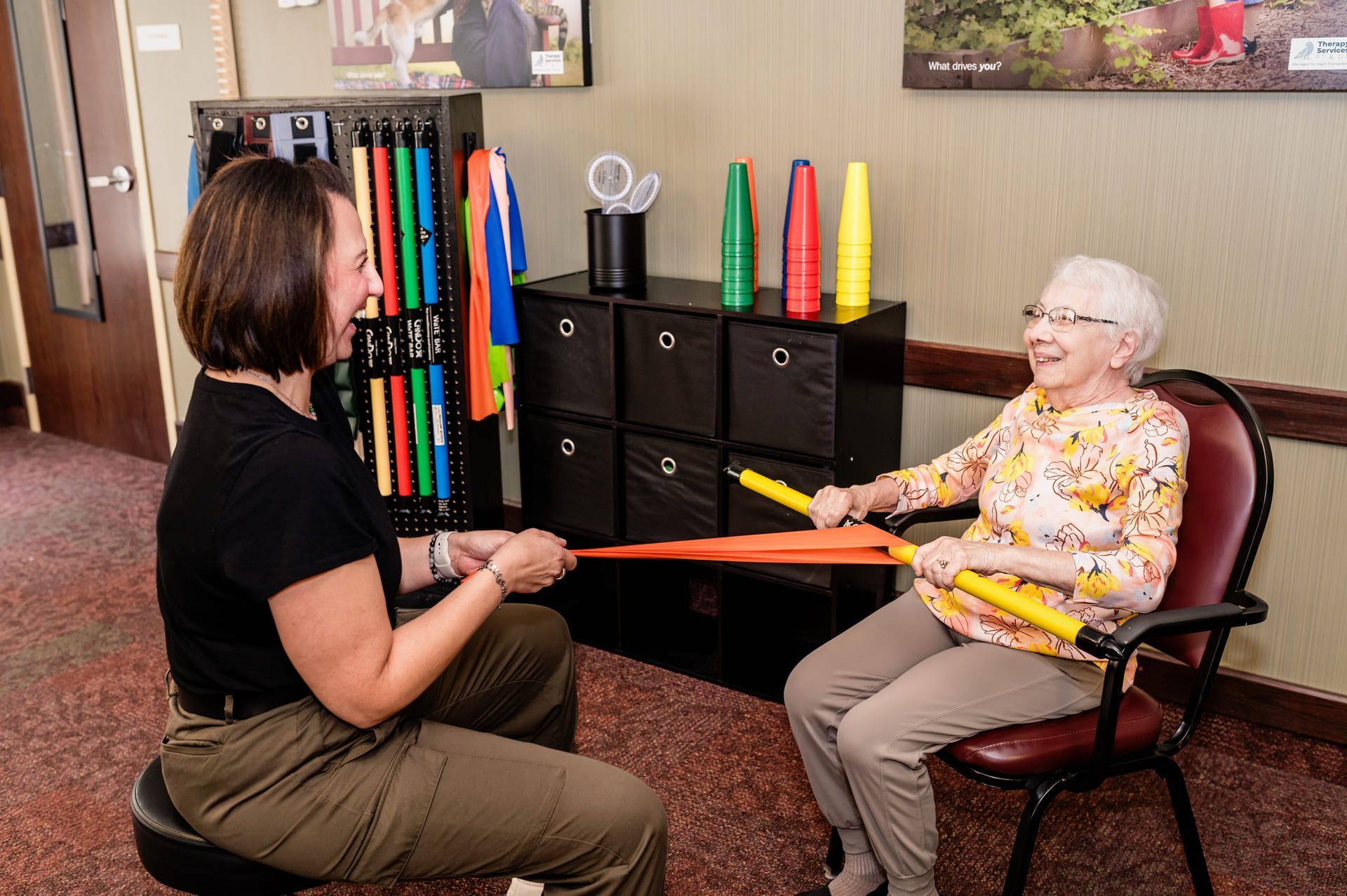 a nurse is helping an elderly woman do exercises on a ball as part of geriatric physical therapy