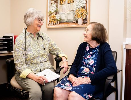 a nurse laughs while talking to an elderly man